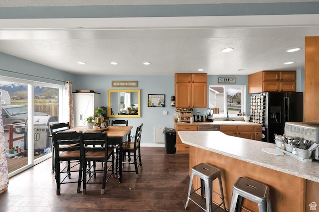 4104 Rose Springs Rd Unit 406, Erda, UT 84074 - kitchen featuring brown cabinets, dark wood finished floors, light countertops, a kitchen bar, and black fridge