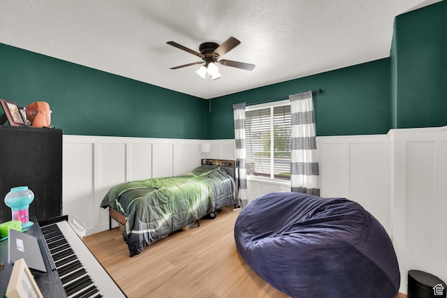 4104 Rose Springs Rd Unit 406, Erda, UT 84074 - bedroom featuring a decorative wall, wood finished floors, a textured ceiling, wainscoting, and ceiling fan