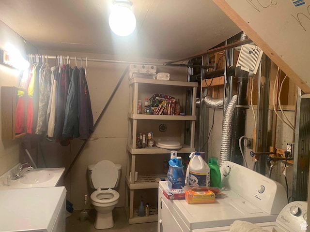 bathroom featuring toilet, separate washer and dryer, and a sink