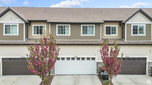 multi unit property featuring stucco siding, an attached garage, a shingled roof, and concrete driveway