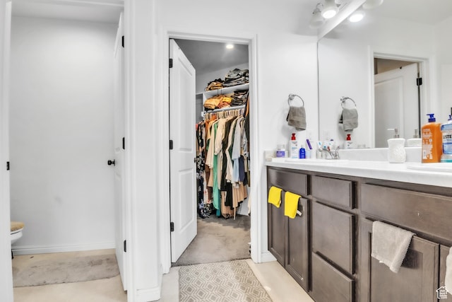 bathroom with a spacious closet, toilet, and vanity