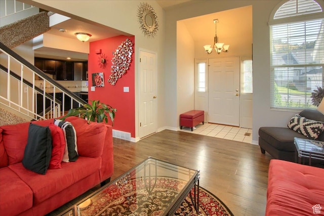 living room with baseboards, a notable chandelier, wood finished floors, and stairs