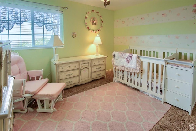 carpeted bedroom featuring wallpapered walls and a crib