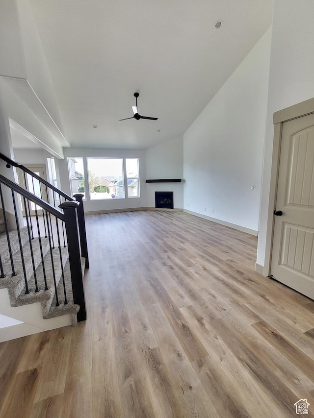 5682 W 7220 S, West Jordan, UT 84081 - unfurnished living room featuring light wood-type flooring, baseboards, a ceiling fan, stairs, and a fireplace