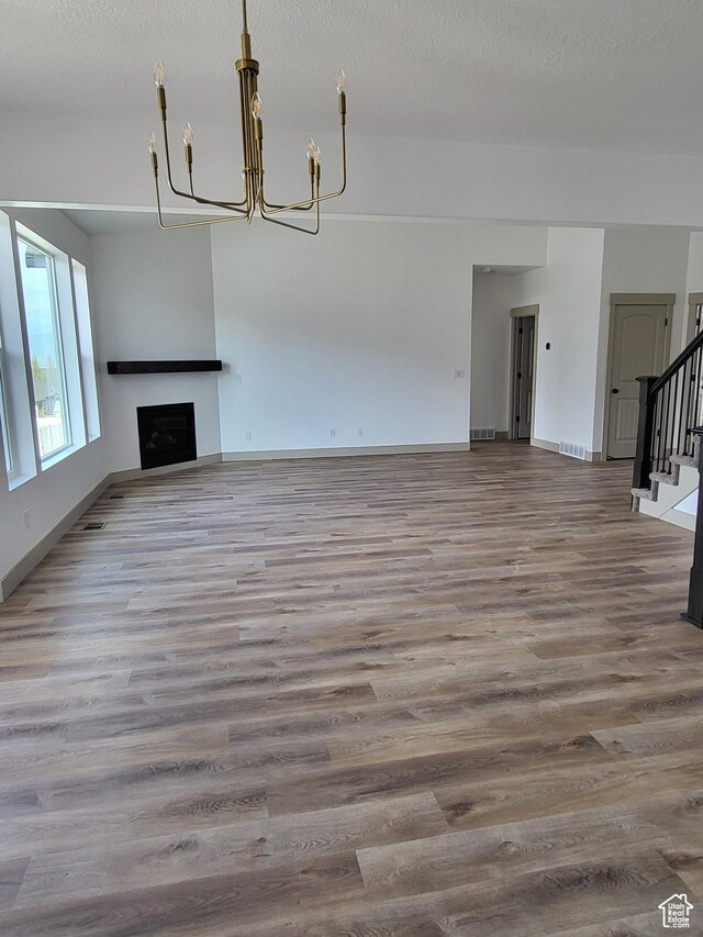5682 W 7220 S, West Jordan, UT 84081 - unfurnished living room featuring stairs, baseboards, wood finished floors, and a notable chandelier