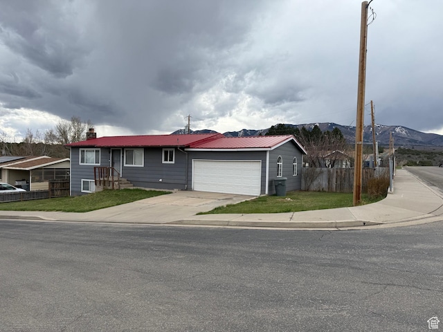 ranch-style home with a chimney, fence, driveway, a mountain view, and a garage