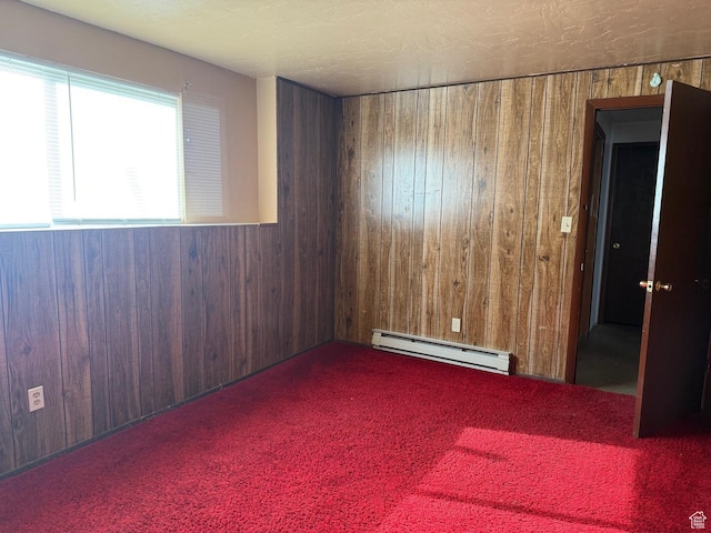 unfurnished room with baseboard heating, carpet floors, and wood walls
