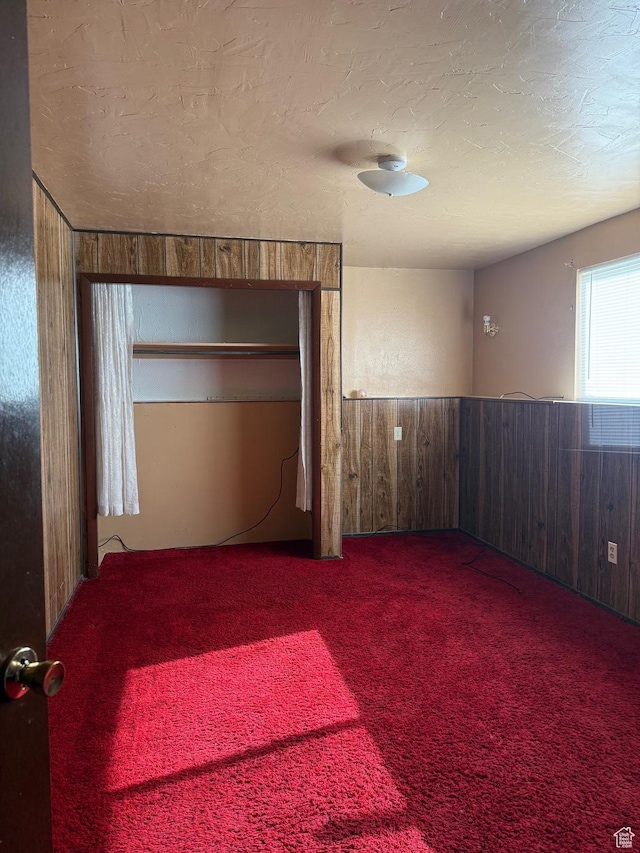 unfurnished room with wooden walls, carpet floors, and a textured ceiling