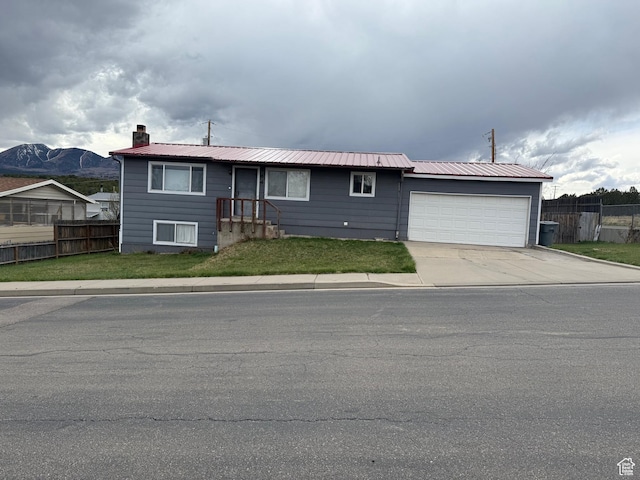 ranch-style home featuring a chimney, fence, a front lawn, an attached garage, and driveway