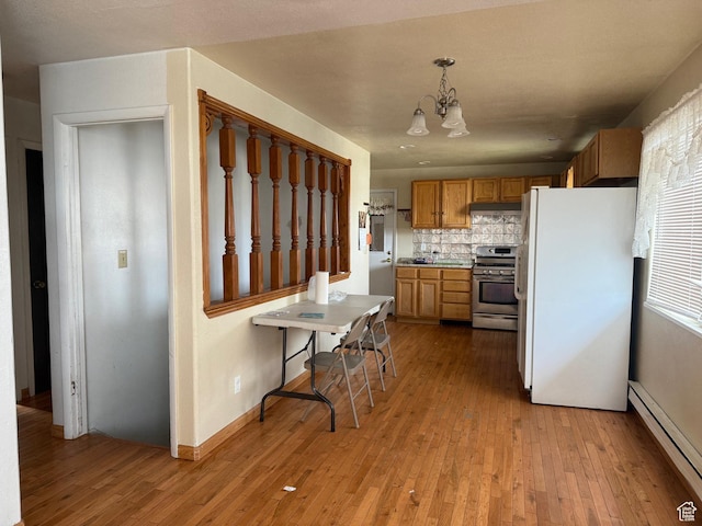 kitchen with a baseboard heating unit, light wood-type flooring, a notable chandelier, stainless steel gas range oven, and freestanding refrigerator