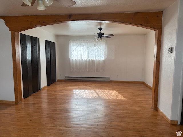 interior space with hardwood / wood-style flooring, arched walkways, and a baseboard radiator