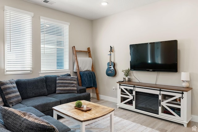 living room with visible vents, light wood-style flooring, and baseboards