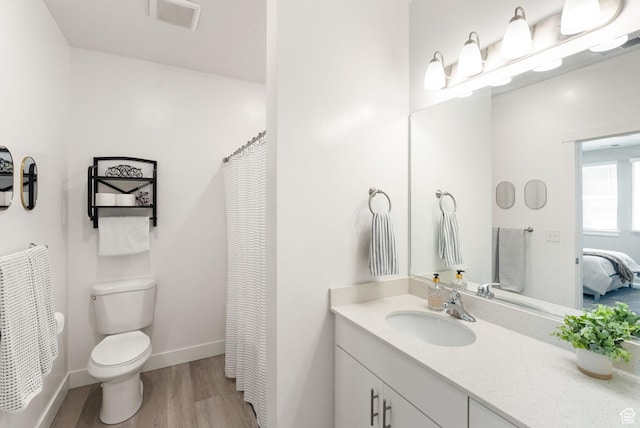 bathroom featuring toilet, visible vents, wood finished floors, vanity, and connected bathroom