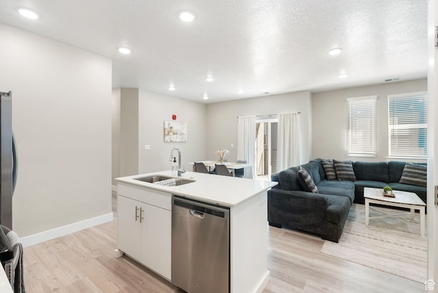 kitchen featuring stainless steel dishwasher, a sink, light wood-style floors, a kitchen island with sink, and white cabinets