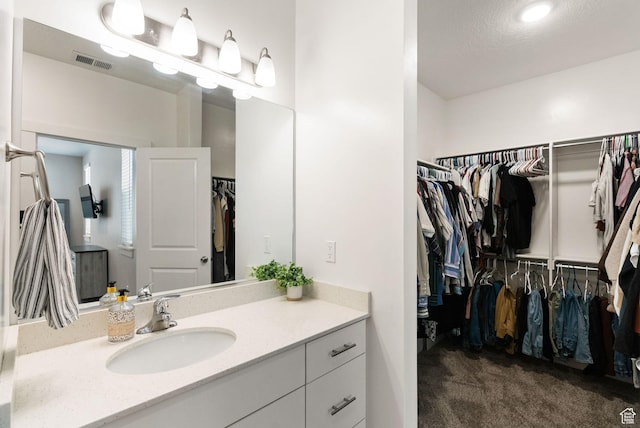 bathroom featuring a walk in closet, vanity, and visible vents