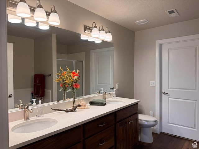 full bathroom with a shower stall, wood finished floors, a sink, and double vanity