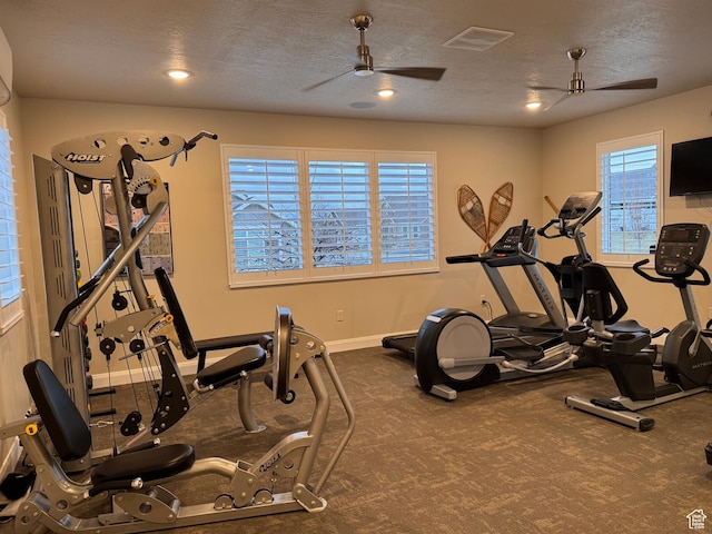 gym featuring a textured ceiling, a ceiling fan, baseboards, and visible vents