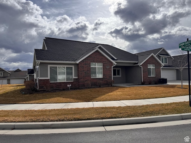 view of front of home featuring brick siding, a shingled roof, and a front lawn