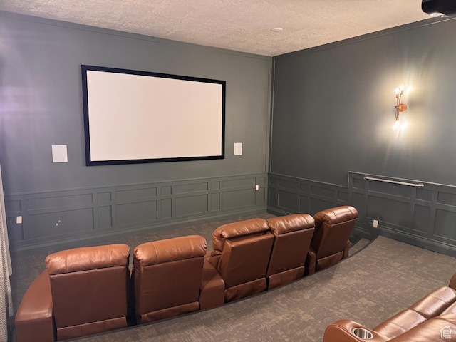 carpeted home theater room featuring a wainscoted wall, a textured ceiling, and a decorative wall