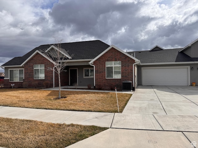 view of front of property with a shingled roof, an attached garage, driveway, brick siding, and a front yard