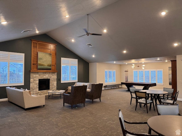 carpeted living area featuring a stone fireplace, ceiling fan with notable chandelier, baseboards, lofted ceiling, and visible vents