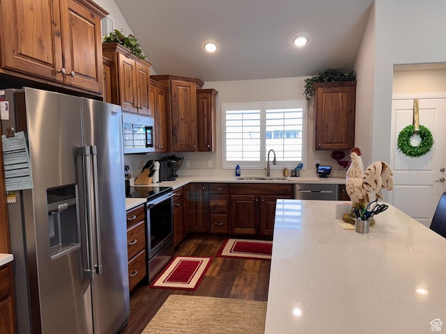 kitchen with recessed lighting, dark wood finished floors, light countertops, a sink, and appliances with stainless steel finishes
