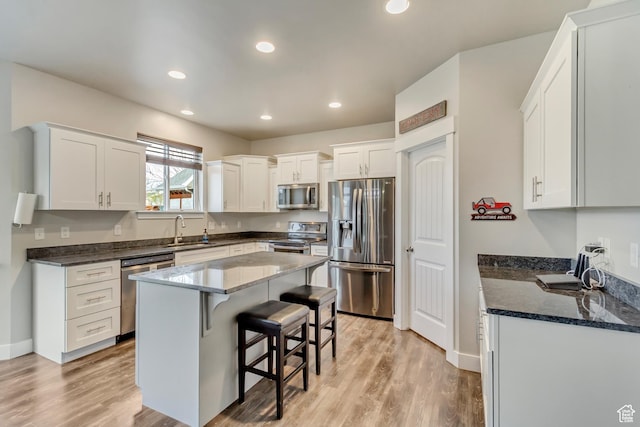 8459 N Western Gailes Dr, Eagle Mountain, UT 84005 - kitchen with dark stone counters, a sink, stainless steel appliances, a kitchen bar, and white cabinetry