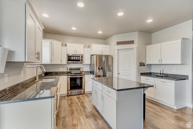 8459 N Western Gailes Dr, Eagle Mountain, UT 84005 - kitchen with light wood-style flooring, dark stone countertops, appliances with stainless steel finishes, and a sink