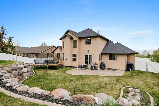 5701 W Emmeline Dr, Herriman, UT 84096 - rear view of property featuring a fenced backyard, a gate, a trampoline, a patio, and stucco siding