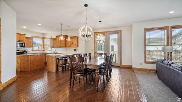 dining space with dark wood-type flooring, baseboards, a notable chandelier, and recessed lighting