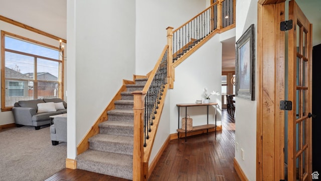 stairs featuring a wealth of natural light, a towering ceiling, hardwood / wood-style floors, and baseboards