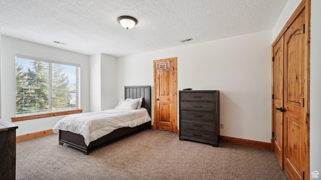 carpeted bedroom with a textured ceiling, baseboards, and visible vents