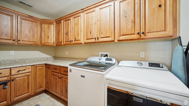 laundry area with visible vents, light tile patterned floors, independent washer and dryer, cabinet space, and a textured ceiling