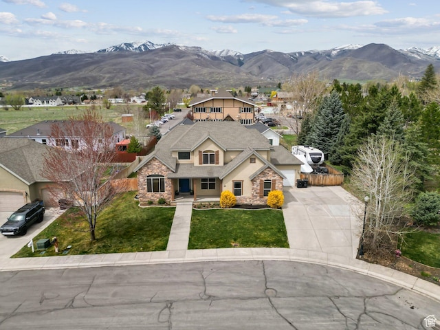 exterior space with concrete driveway, a mountain view, and stone siding
