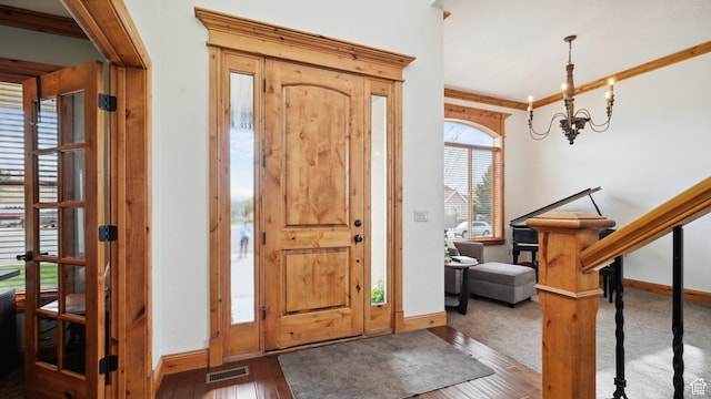foyer with baseboards, visible vents, a notable chandelier, and wood-type flooring