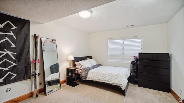 carpeted bedroom featuring baseboards, a textured ceiling, and visible vents