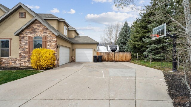 view of side of home featuring stone siding, driveway, a garage, and stucco siding