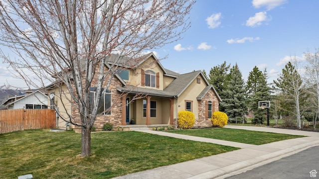 view of front of house with stone siding, a front lawn, stucco siding, and fence
