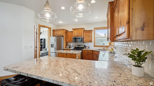 kitchen featuring a sink, brown cabinets, stainless steel appliances, backsplash, and light stone countertops