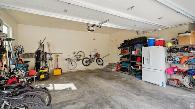 garage featuring white fridge with ice dispenser and a garage door opener