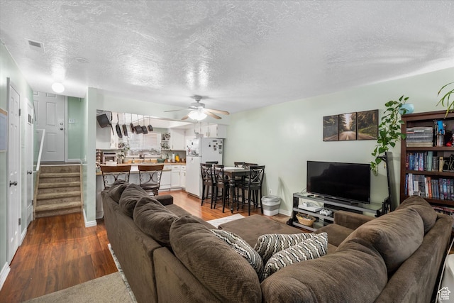 living room with wood finished floors, a textured ceiling, a ceiling fan, and stairway