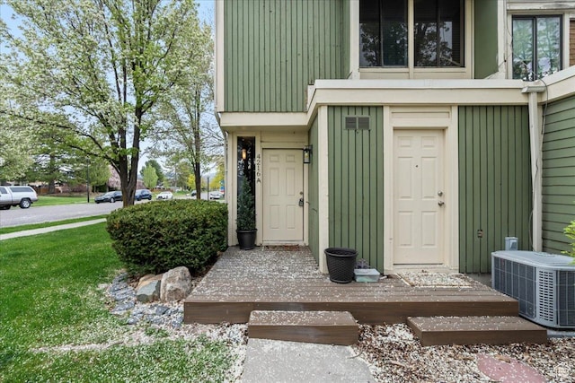 view of exterior entry featuring central air condition unit and board and batten siding