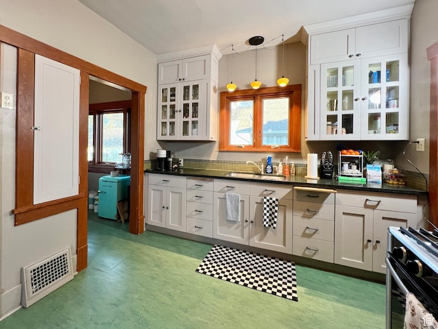 kitchen featuring glass insert cabinets, visible vents, white cabinetry, and light floors