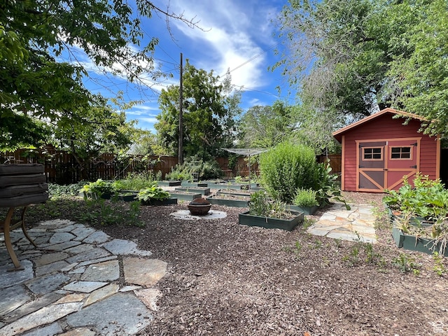view of yard with a storage shed, a garden, a fenced backyard, and an outdoor structure