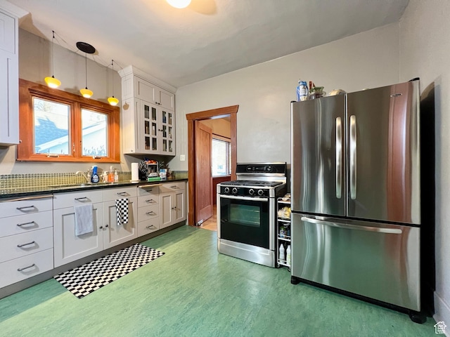 kitchen featuring gas range oven, freestanding refrigerator, dark countertops, and white cabinets