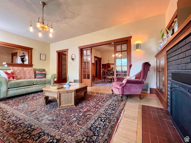 living room with a fireplace with flush hearth, a chandelier, and wood finished floors