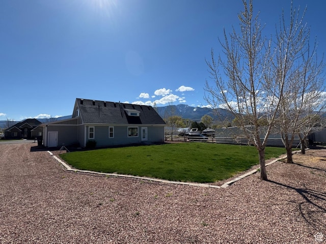 rear view of property featuring a lawn, fence, and a mountain view