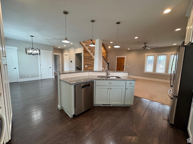 kitchen with baseboards, a sink, appliances with stainless steel finishes, and open floor plan