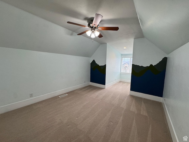 additional living space featuring baseboards, light colored carpet, lofted ceiling, and visible vents