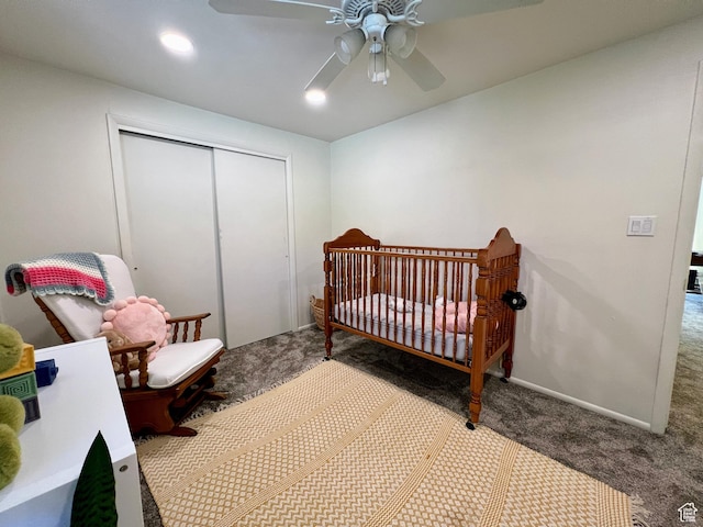 bedroom with a nursery area, a closet, carpet flooring, and a ceiling fan